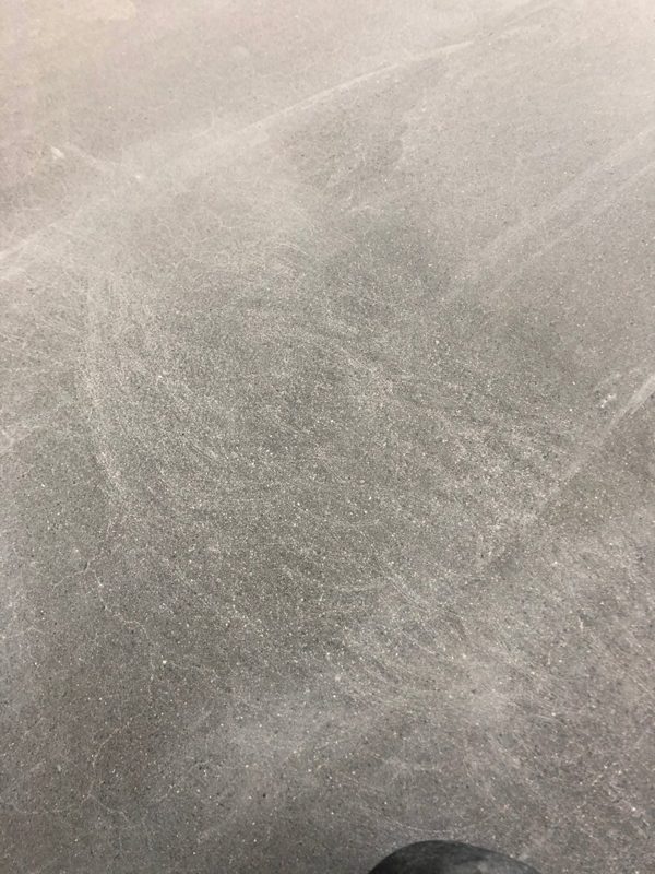 Zdjęcie szarej posadzki betonowej z kolistymi rysami, wysłane do obu asystentów